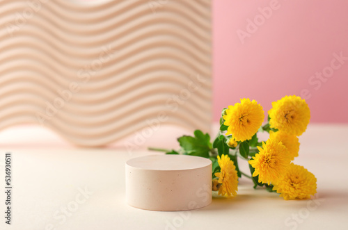 Round podium for the presentation of products and cosmetics. Empty stand for packaging. Cosmetic beauty showcase with yellow chrysanthemum flowers.