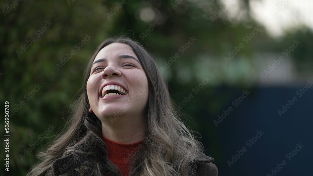 One happy casual Brazilian hispanic young woman laughing and smiling portrait face closeup standing outdoors One happy casual Brazilian hispanic young woman laughing and smiling portrait face closeup standing outdoors