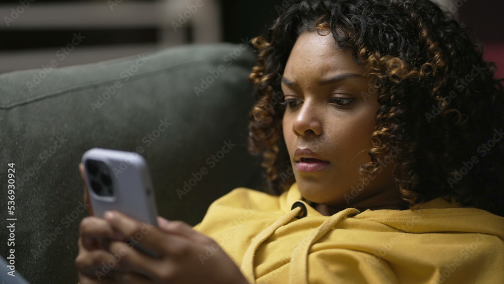 One frustrated young black woman angry on social media cellphone device. Upset African American girl feeling anxious about notification message One frustrated young black woman angry on social media cellphone device. Upset African American girl feeling anxious about notification message