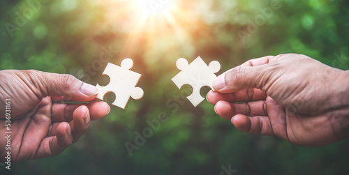 Hands holding jigsaw puzzles on green bokeh nature backgounds, Business matching concept.
 photo