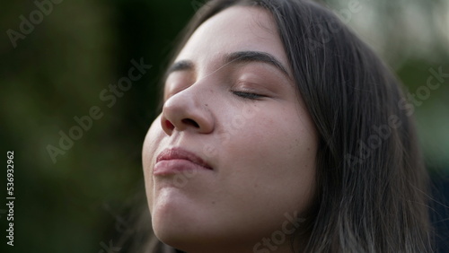 Young woman closing eyes in meditation closeup face. Person smiling with HOPE