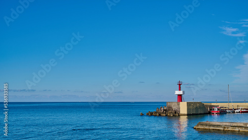 Panoramic view of little red lighthouse on the pier against the blue sky on sunny day, copy space © Vitaliy