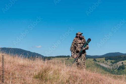 army soldier holding a sniper rifle with scope and walking in the forest. war, army, technology and people concept. 