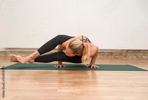 yogi woman practicing yoga concept, standing in Astavakrasana exercise photo