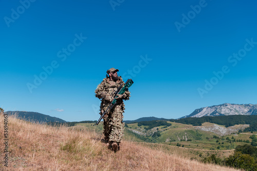 army soldier holding a sniper rifle with scope and walking in the forest. war, army, technology and people concept. 