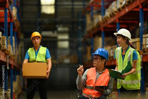 Young female warehouse worker and senior male managers in wheelchair checking newly arrived goods in large retail warehouse