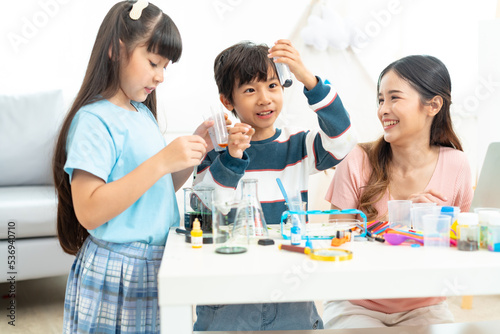 Kid playing a microscope for scientific experiments at home.Young beautiful teacher and toddlers playing on the floor with lots of toys at kindergarten 