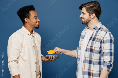 Side ivew young two friends happy fun men 20s wear white casual shirt together hold wireless modern bank payment terminal to process acquire credit card isolated plain dark royal navy blue background photo