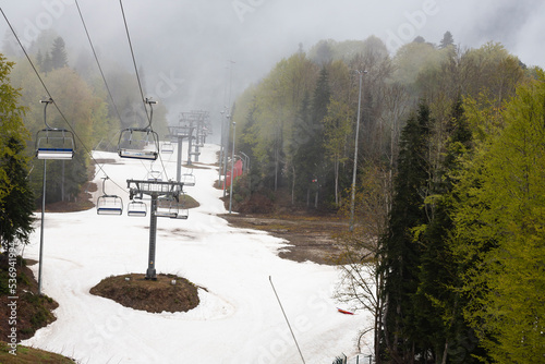 Empty chairlift in ski resort. Shot in summer with green grass and very little snow toned photo