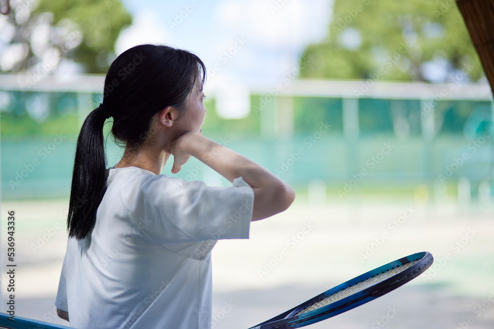 テニスコートでテニスをする若い日本人女性