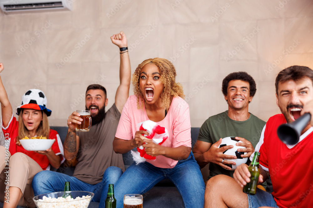 Obraz premium Football fans watching the game on TV, celebrating after their team scoring a goal
