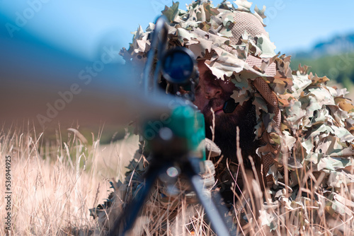 Fotografie, Obraz army soldier holding sniper rifle with scope and aiming in forest