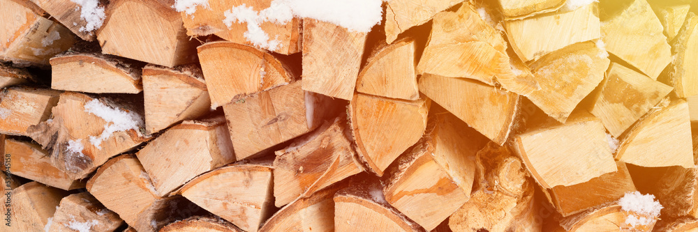 textured firewood background chopped wood for kindling. woodpile stacked firewood birch tree covered fresh icy frozen snow and snowflakes. cold weather and snowy winter time season. banner. flare textured firewood background chopped wood for kindling. woodpile stacked firewood birch tree covered fresh icy frozen snow and snowflakes. cold weather and snowy winter time season. banner. flare