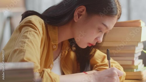 Close Up Of Young Asian Female Writing On The Book While Studying At Home
 photo