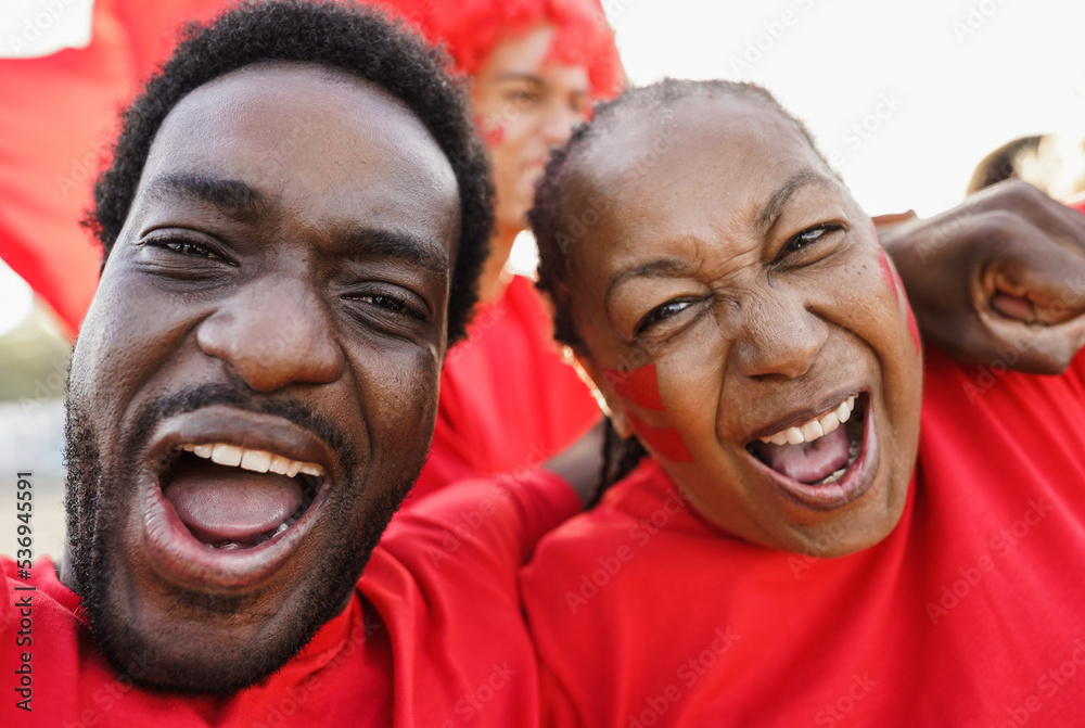 African red sport fans screaming while supporting their team - Football supporters having fun at competion event - Champions and winning concept - Focus on woman face nose