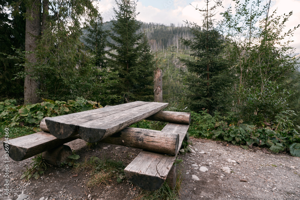 Fototapeta premium Empty outdoor wooden furniture in the Tatra National Park. Concept of having a picnic outdoors with a beautiful mountain view.