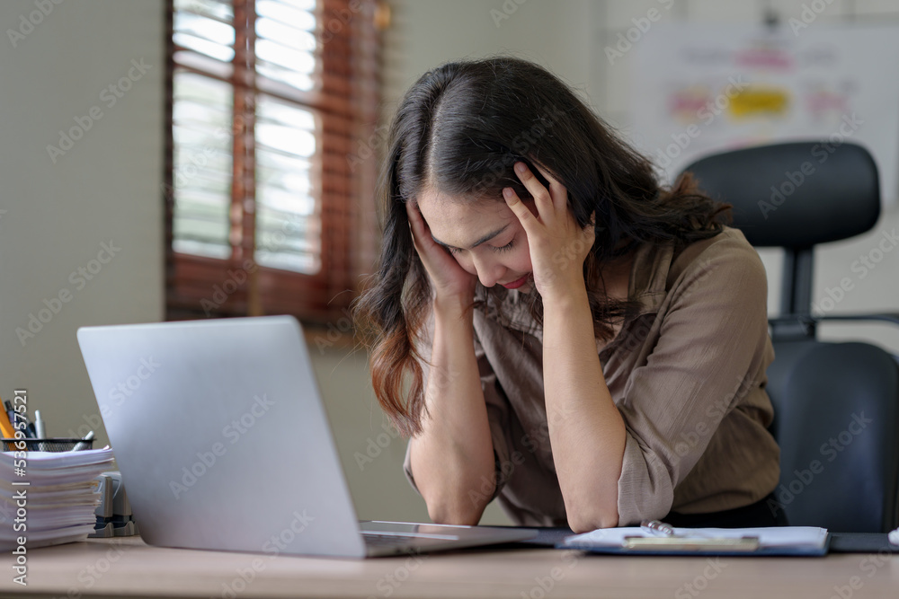 Asian businesswoman sitting in the office feeling tired, stressed or exhausted from a long day at work. Asian businesswoman sitting in the office feeling tired, stressed or exhausted from a long day at work.
