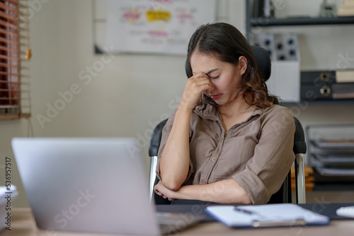 Asian businesswoman sitting in the office feeling tired, stressed or exhausted from a long day at work.