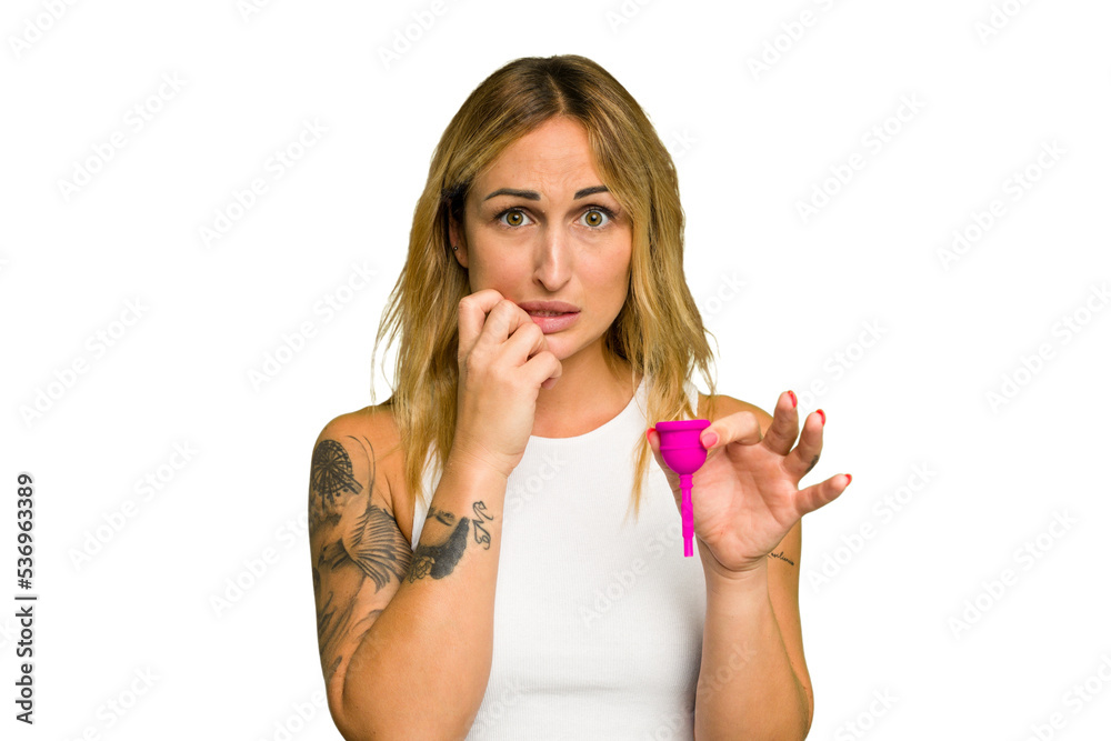 Young caucasian woman holding menstrual cup isolated on green chroma background biting fingernails, nervous and very anxious. Young caucasian woman holding menstrual cup isolated on green chroma background biting fingernails, nervous and very anxious.