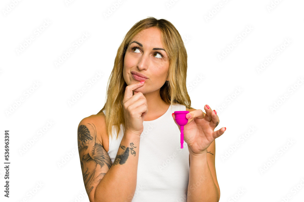 Young caucasian woman holding menstrual cup isolated on green chroma background looking sideways with doubtful and skeptical expression. Young caucasian woman holding menstrual cup isolated on green chroma background looking sideways with doubtful and skeptical expression.