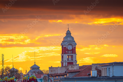 Old tower clock of railway station of Varna city, Bulgaria and flying birds at sunset photo