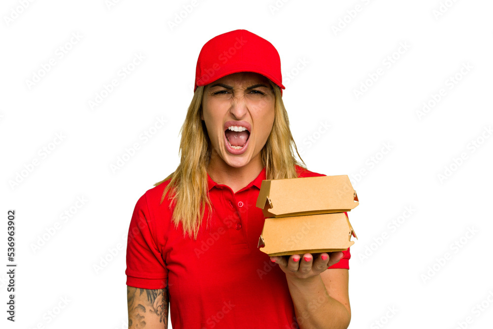 Young caucasian delivery woman holding a burger isolated on green chroma background screaming very angry and aggressive. Young caucasian delivery woman holding a burger isolated on green chroma background screaming very angry and aggressive.