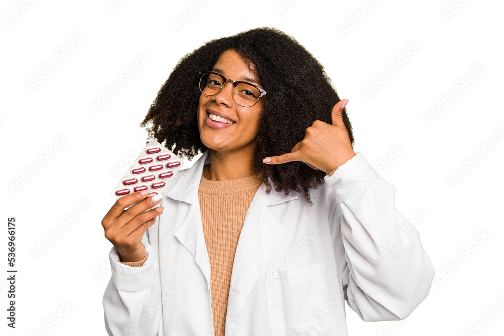 Young pharmacist African American woman holding a tablet of pills isolated showing a mobile phone call gesture with fingers. Young pharmacist African American woman holding a tablet of pills isolated showing a mobile phone call gesture with fingers.