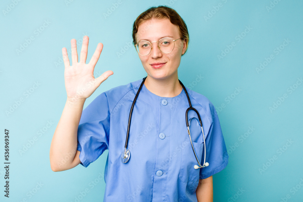 Young nurse caucasian woman isolated on blue background smiling cheerful showing number five with fingers. Young nurse caucasian woman isolated on blue background smiling cheerful showing number five with fingers.