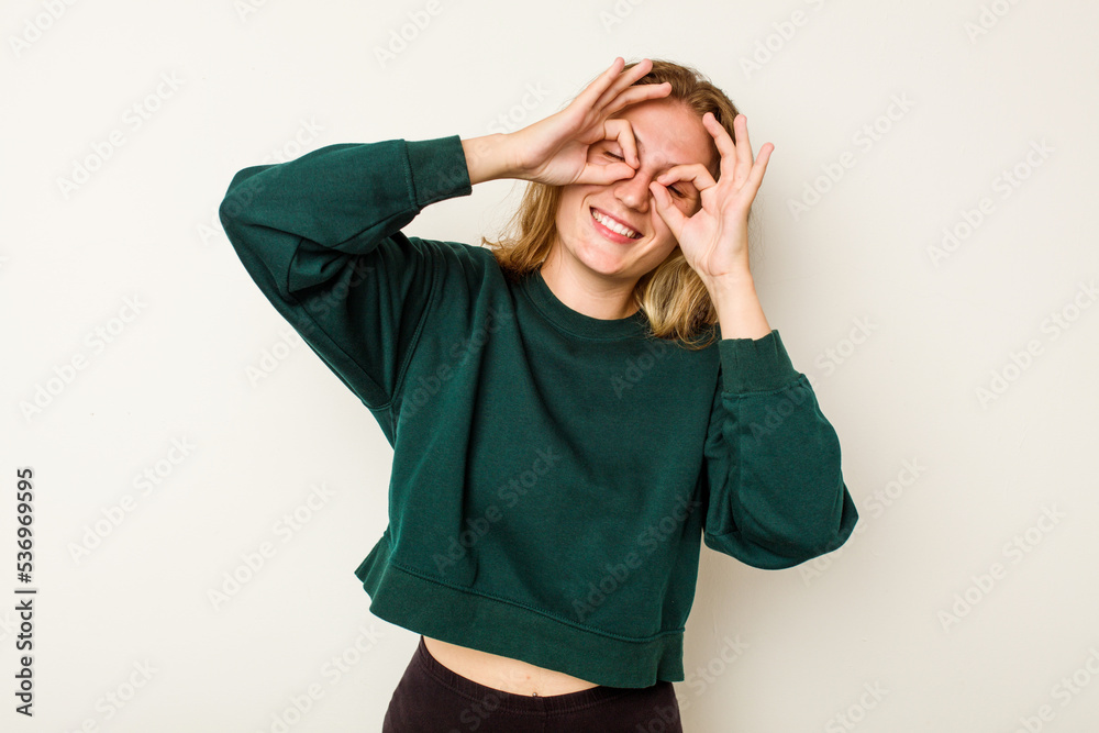 Young caucasian woman isolated on white background showing okay sign over eyes Young caucasian woman isolated on white background showing okay sign over eyes