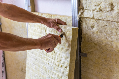 Worker insulating a room wall with mineral rock wool thermal insulation. photo