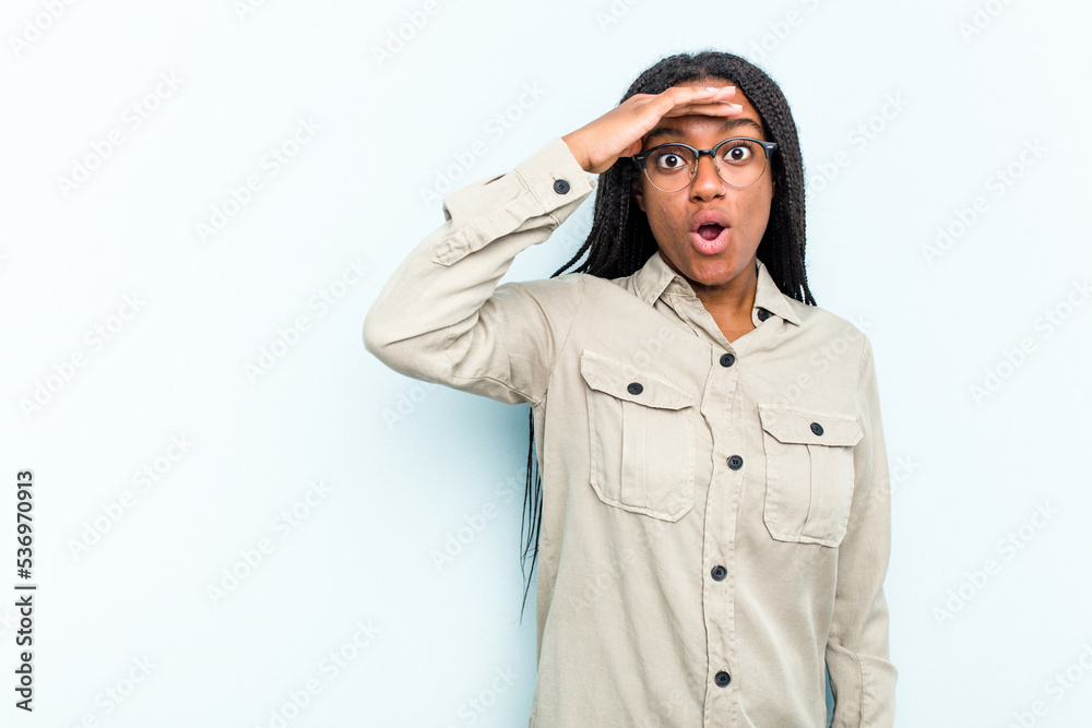 Young African American woman with braids hair isolated on blue background looking far away keeping hand on forehead. Young African American woman with braids hair isolated on blue background looking far away keeping hand on forehead.