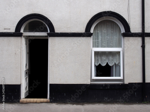 open front door and window of a typical old brick british terraced house with black and white decorative paintwork
