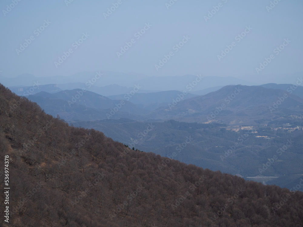 Mountain landscape with brown hill in the front and subsequent mountains that reach the horizon