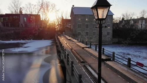 Manotick Mill located in Ottawa. Golden sunshine in late fall early winter. Showcasing the beautiful mill, dam, freezing rideau river with ice forming.  photo