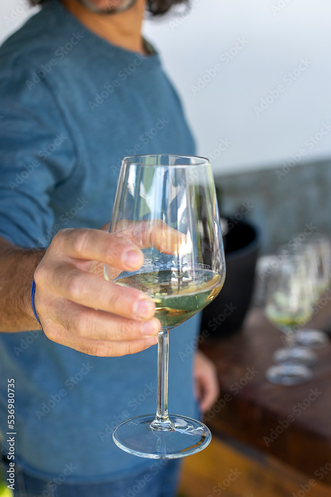 Man hand holding out a wine glass in a celebration. Closeup.