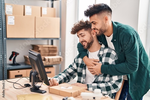 Young couple ecommerce business workers hugging each other working at office