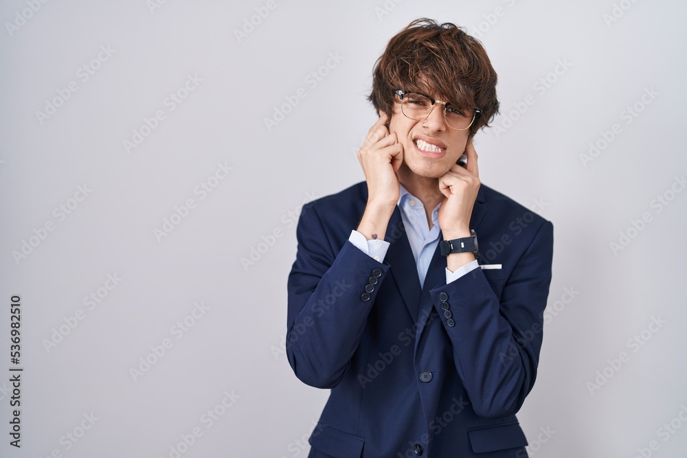 Hispanic business young man wearing glasses covering ears with fingers with annoyed expression for the noise of loud music. deaf concept. Hispanic business young man wearing glasses covering ears with fingers with annoyed expression for the noise of loud music. deaf concept.