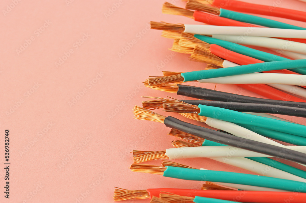 Copper electrical wires in colored insulation on a colored background close-up.