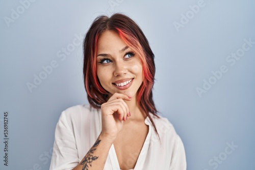 Young caucasian woman wearing casual white shirt over isolated background with hand on chin thinking about question, pensive expression. smiling and thoughtful face. doubt concept.
