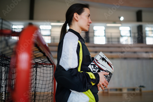 Close-up of woman floorball goalkeeper in helmet concetrating on game in gym. photo