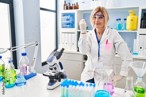 Middle age blonde woman working at scientist laboratory doing italian gesture with hand and fingers confident expression