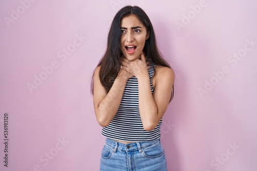 Young teenager girl wearing casual striped t shirt shouting and suffocate because painful strangle. health problem. asphyxiate and suicide concept.