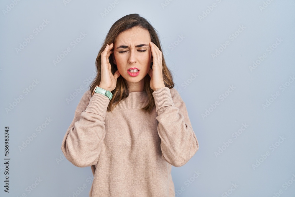 Young woman standing over isolated background with hand on head, headache because stress. suffering migraine. Young woman standing over isolated background with hand on head, headache because stress. suffering migraine.