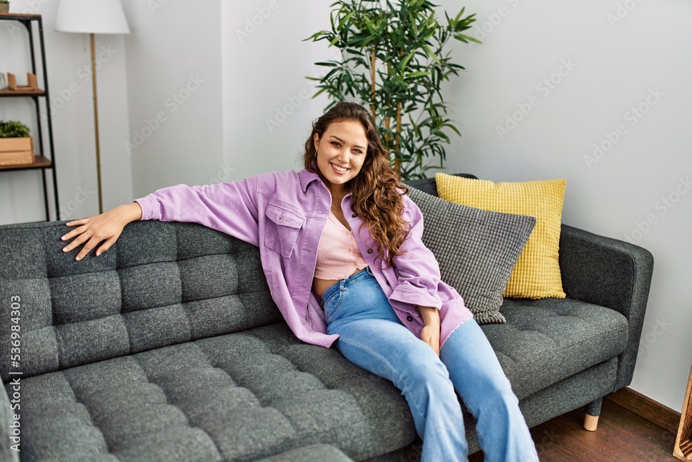 Obraz premium Young beautiful hispanic woman smiling confident sitting on sofa at home