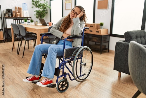 Young beautiful hispanic woman business worker smiling confident sitting on wheelchair at office