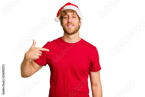 Young caucasian man wearing a Christmas Santa hat isolated on white background person pointing by hand to a shirt copy space, proud and confident