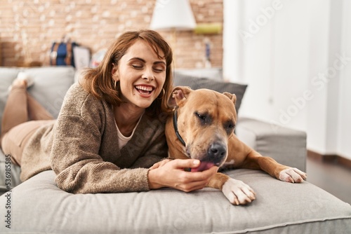 Young caucasian woman smiling confident lying on sofa with dog at new home