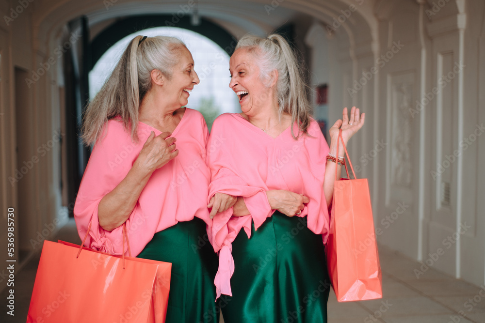 Happy senior women twins in colourful clothes in city, shopping. Happy senior women twins in colourful clothes in city, shopping.