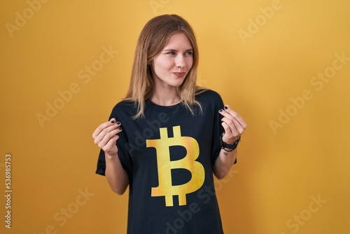 Obraz na płótnie Blonde caucasian woman wearing bitcoin t shirt doing money gesture with hands, a