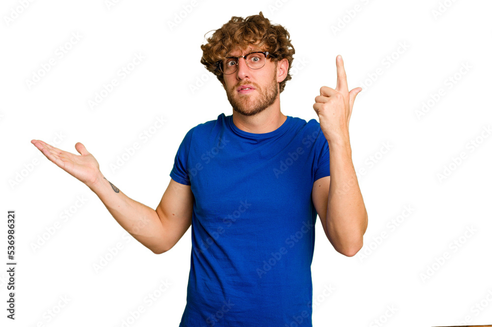 Young caucasian man isolated on green chroma background holding and showing a product on hand.